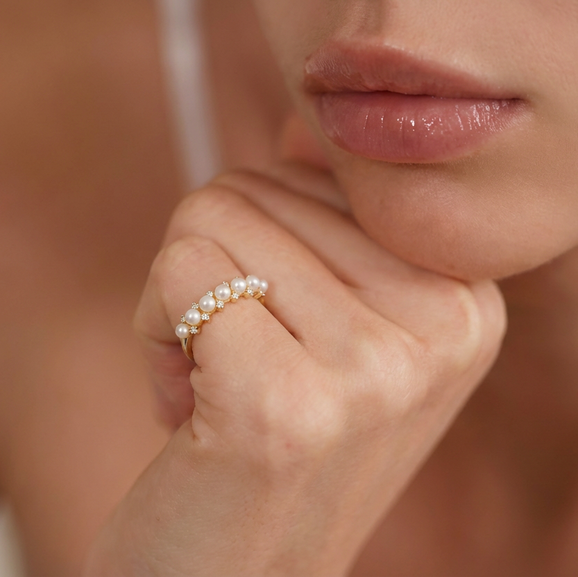 Close-up of a hand wearing a pearl ring with a blurred background